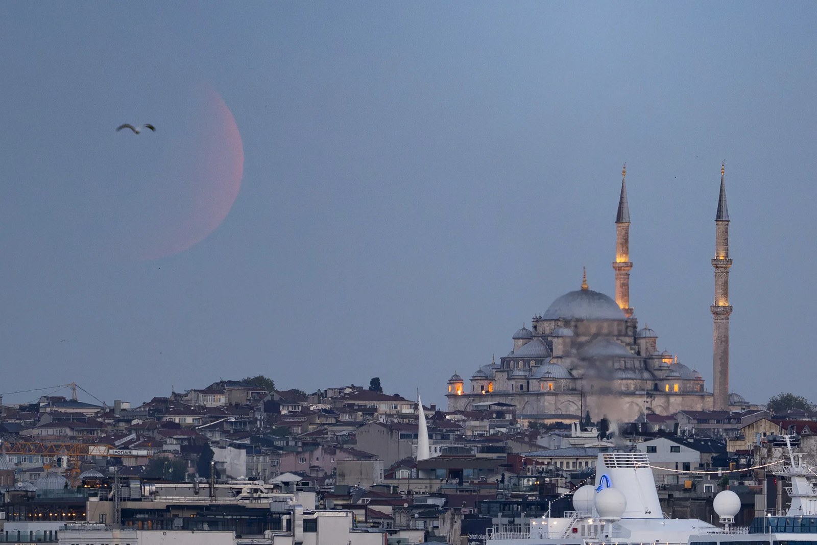 A faint red moon above a mosque.