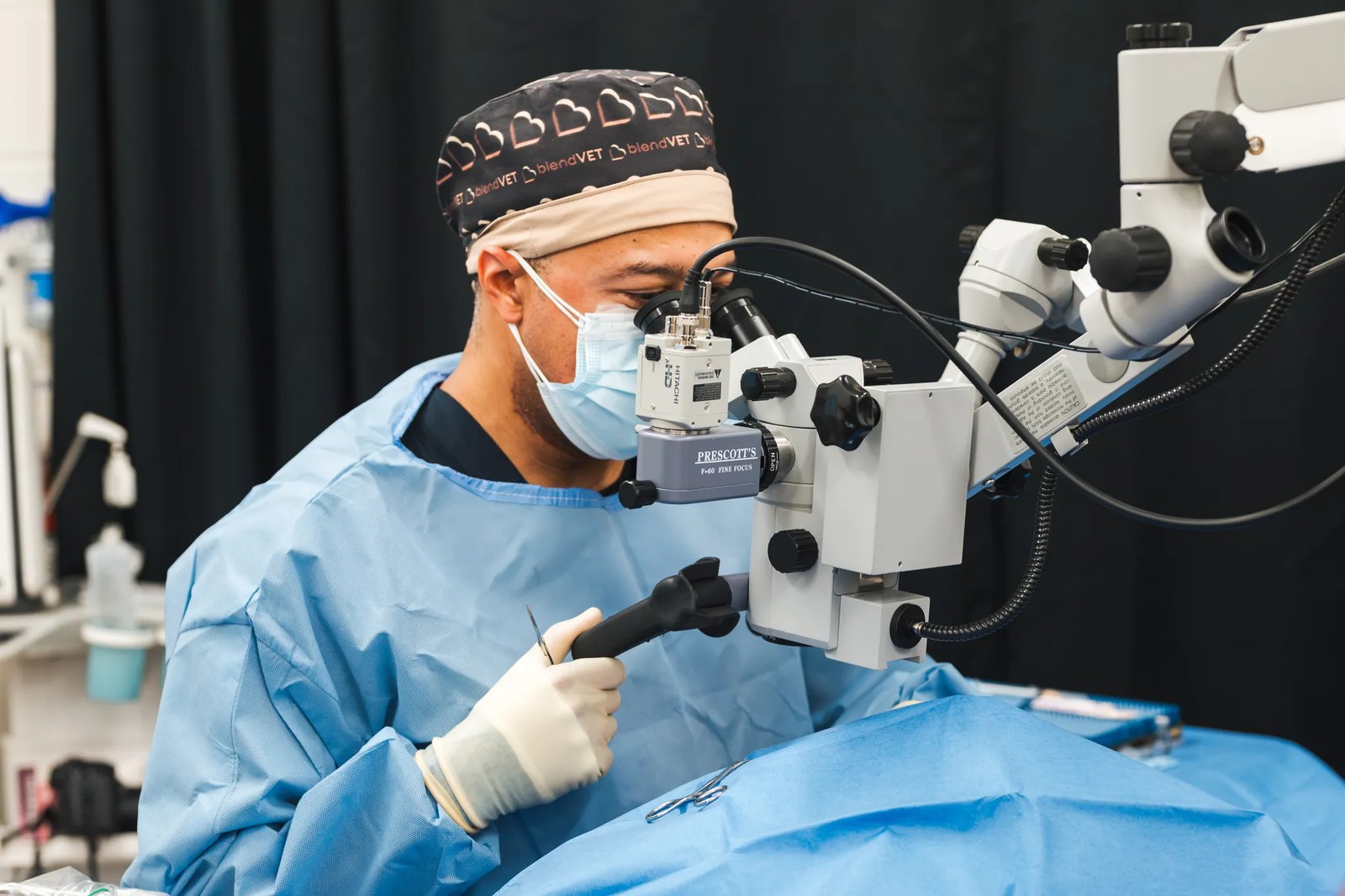 a man in blue scrubs performs and eye surgery