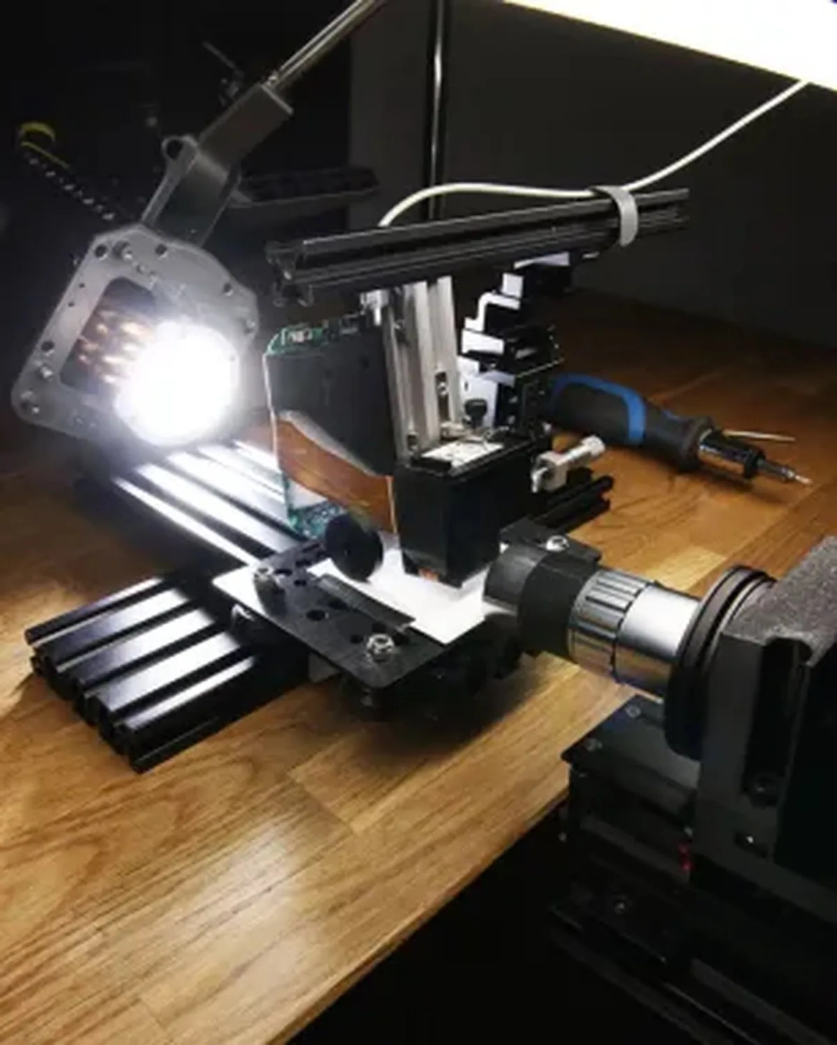 A metal contraption on a workstation lit by a single white bulb.
