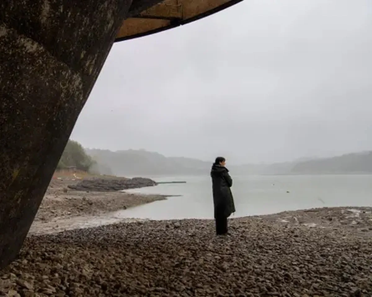 Pippa stands on a rocky shore of Ardingly reservoir, an area normally underwater