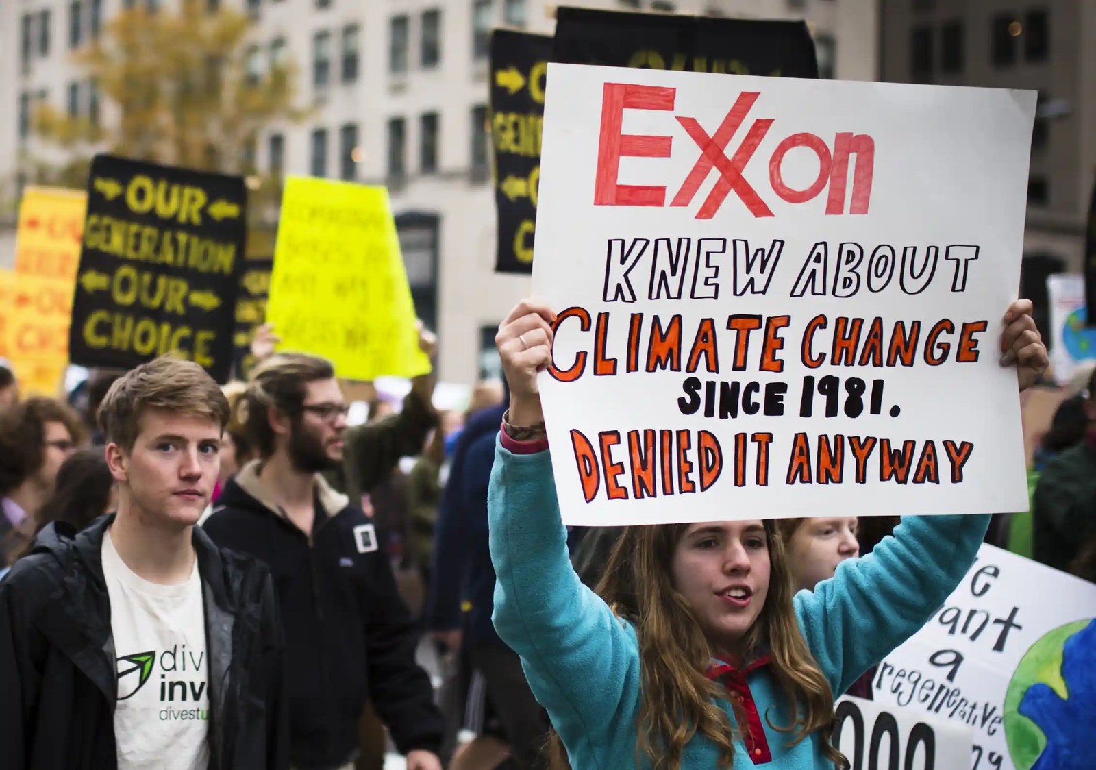 A group of people holding signs, including one reading 'Exxon knew about climate change since 1981, denied it anyway.'