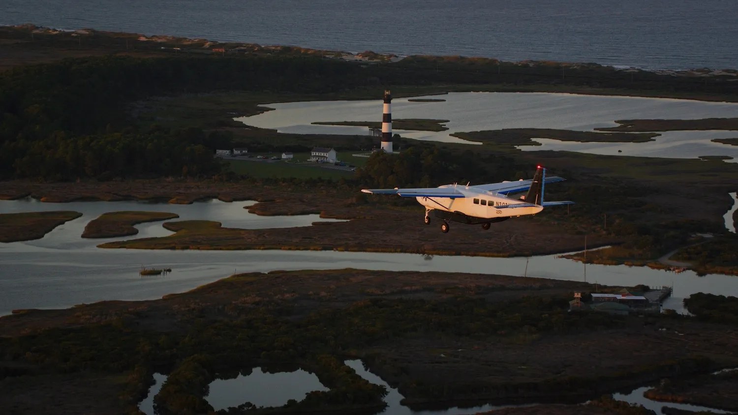 Cessna airplane flying above South Carolina coast with marshes and lighthouse beneath it