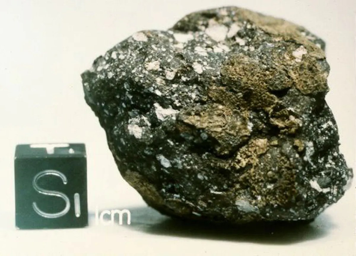 A rocky conglomerate with a 1-centimeter cube next to it for scale.
