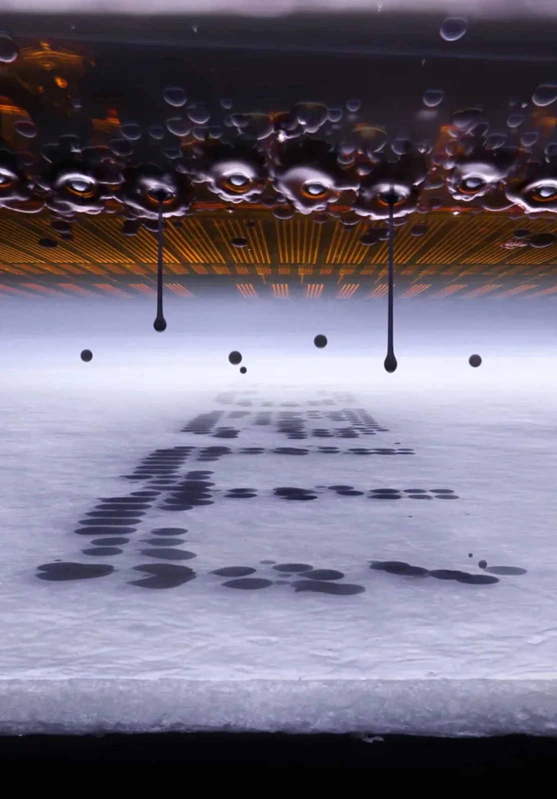 Droplets of ink hang suspended between a printer’s nozzles and the paper below.